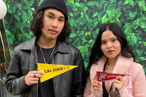 Two recent high school graduates holding college pennants from Cal State LA and Cal State Northridge